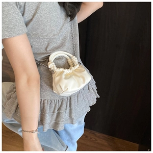 Detail view of mini white pleated cloud bag with silver chain strap and top handle