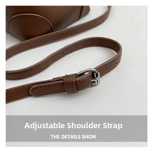 Detail of adjustable brown leather shoulder strap with polished silver metal buckle