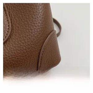 Close-up of litchi grain leather texture and durable stitching on brown bucket bag
