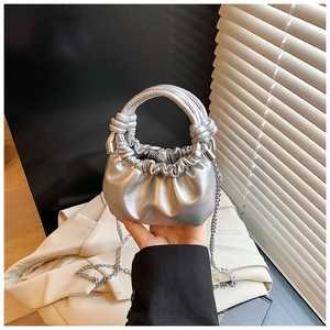 Detail of silver metallic cloud bag with round handle and detachable chain strap