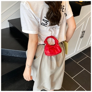 Detailed view of red mini shoulder bag with knot handle and silver chain strap
