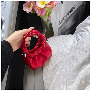 Close-up of bright red pleated PU mini bag with silver metallic buckle detail in car