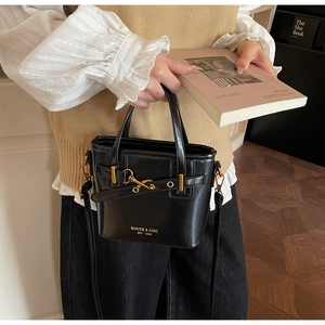 Detail of black glossy leather bucket bag with gold hardware and Maven Chic logo