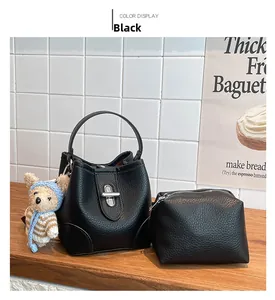 Close-up of black litchi leather bucket bag set with mini pouch and cute bear pendant
