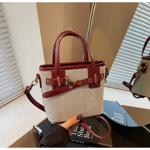 Detail of canvas bucket bag with brown leather trim and golden metal hook closure