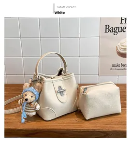 White pebbled leather bucket bag set with silver buckle and cute teddy bear charm