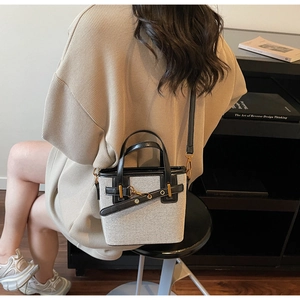 Lifestyle shot of a canvas and black leather small bucket bag worn by a model