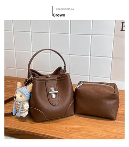 Detail view of brown pebbled leather bucket bag with silver turn-lock and bear pendant