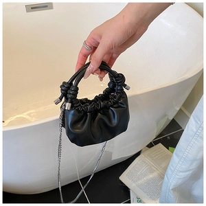 Detail of black pleated PU mini bag featuring knotted handle and silver chain strap