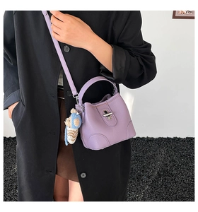 Detail of purple bucket bag with metallic twist lock and cute bear charm accessory