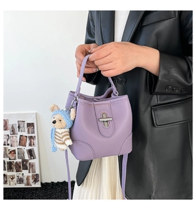 Detail of lilac bucket bag with lychee texture, silver twist lock and cute teddy bear charm