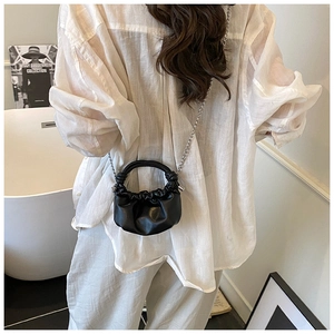 Crossbody view of a black pleated cloud mini bag with a refined silver chain strap
