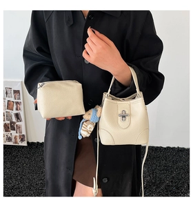 Detail of cream bucket bag in lychee leather with teddy bear charm and small pouch