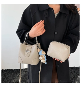 Detail of taupe lychee pattern bucket bag with teddy charm and matching inner pouch