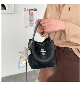 Close-up of black pebble leather bucket bag with silver lock and teddy bear charm