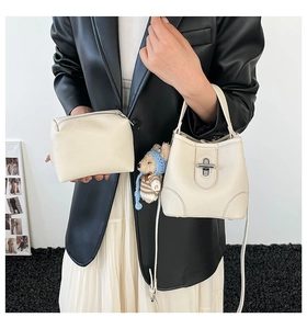 Creamy white bucket bag detail with textured leather, silver lock and cute bear charm