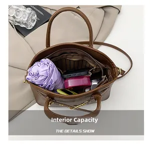 Detail view of brown pebbled leather bag interior with umbrella, phone and makeup