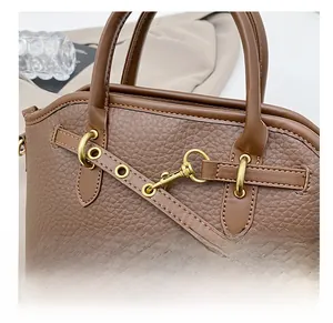 Detail of brown litchi pattern leather handbag with gold clasp and fine stitching