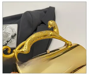 Detailed macro view of luxury gold panther-shaped handle on a cylindrical acrylic box bag