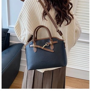 Detail of vintage navy blue pebbled leather bag with brown handles and gold hardware