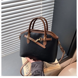Detail of black lychee grain leather bag with brown handles and metal buckle accent