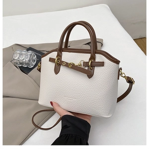 Detail of lychee pattern leather bag with contrast stitching and gold metal buckle