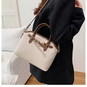 Detail of a vintage-style large capacity shoulder bag in beige with dark brown leather trim