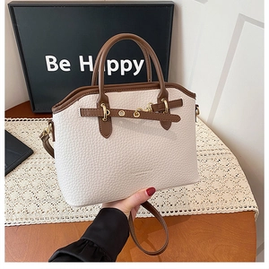 Detail of off-white lychee leather bag with contrast brown trim and golden hardware