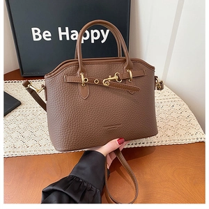 Detail of brown litchi pattern leather bag with golden buckle and fashion logo text