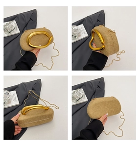 Macro view of woven texture clutch bag featuring U-shaped gold handle and metal chain