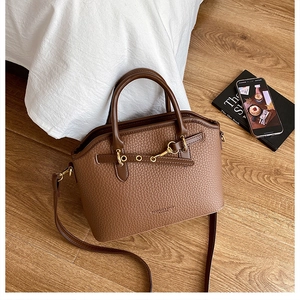 Detail of brown lychee grain leather handbag with gold buckle and detachable strap