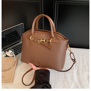 Detailed view of brown lychee grain leather tote with gold hardware and strap on a desk