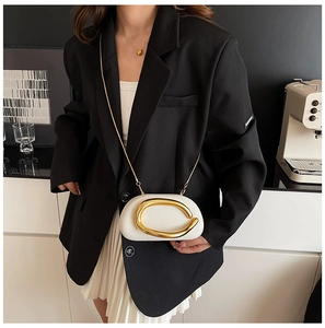 Lifestyle shot of white textured crossbody bag with gold C-buckle on black suit
