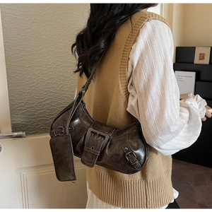 Detailed view of vintage dark brown faux leather underarm bag with cracked texture and charms