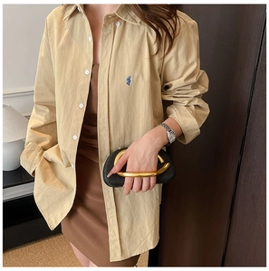 Detail of a khaki long-sleeve cotton shirt featuring a blue embroidered logo on the pocket