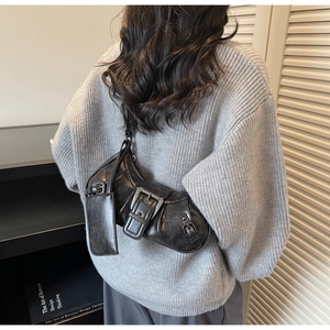 Detail of vintage cracked leather texture and silver buckle accents on a black shoulder bag