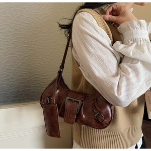 Close-up of vintage brown hobo bag with large metal buckle and textured leather detail