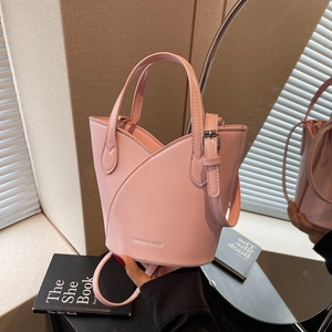 Pink faux leather bucket bag with petal edge design and detachable strap in a home setting