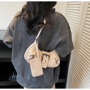 Detail of a beige vintage crossbody bag with metal buckles and a small coin purse charm