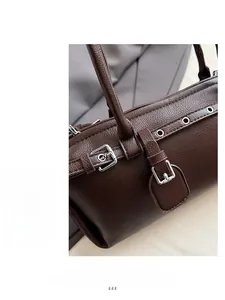 Detail of dark brown lychee leather handbag with silver metallic buckles and neat stitching