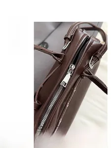 Detail of silver zipper closure and rivets on brown lychee texture leather handbag