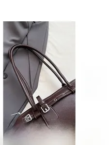Detail of dark brown lychee grain leather shoulder bag with silver buckle and smooth strap