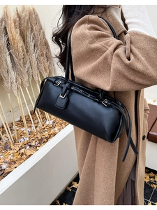 Close-up of black leather baguette bag with silver buckles and decorative straps