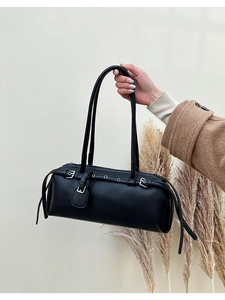 Close-up of black lychee leather handbag with silver buckles and grommet details