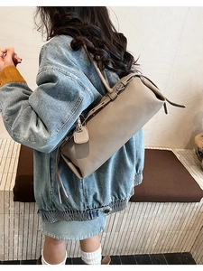 Detail view of elephant gray grained leather Boston bag with belt buckle shoulder strap