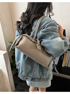 Detail of taupe cylindrical shoulder bag with fine leather texture and metallic buckle