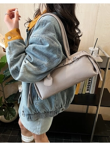 Detailed side view of grey lychee leather baguette bag with silver hardware on model