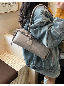 Taupe cylinder shoulder bag in lychee leather featuring a metal clasp and retro buckle strap