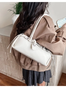 Detail of white lychee leather shoulder bag worn by model in a minimalist room