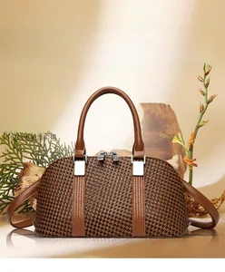 Detail of a brown woven texture Boston bag with leather straps and silver hardware